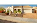 Charming single-story home featuring a tile roof, desert landscaping, and a brick paver driveway at 18322 W Thistle Landing Dr, Goodyear, AZ 85338