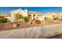 Beautiful home with desert landscaping, featuring mature trees, flowering plants, and stone accents at 18322 W Thistle Landing Dr, Goodyear, AZ 85338