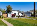 An inviting home shows off its lush lawn, complemented by mature trees and colorful garden beds at 406 W Coolidge St, Phoenix, AZ 85013