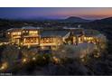 Stunning modern home featuring stone accents, landscape lighting and mountain views at twilight at 42690 N 98Th Pl, Scottsdale, AZ 85262