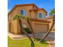 A two-story tan home featuring desert landscaping with multiple palm trees and a red tile roof at 617 N Cobblestone St, Gilbert, AZ 85234