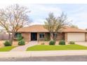 Charming single-story home featuring a manicured front yard, a two-car garage, and a welcoming walkway at 6409 W Riviera Dr, Glendale, AZ 85304