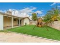 This backyard features a grass area with playset and a covered patio at 7605 W Avalon Dr, Phoenix, AZ 85033