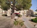 Apartment building with manicured landscaping, mature trees, and visible entrance at 7860 E Camelback Rd # 309, Scottsdale, AZ 85251