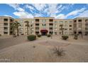 Full exterior shot of a multi-story apartment building with mature landscaping and red awnings at 7860 E Camelback Rd # 309, Scottsdale, AZ 85251