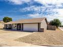View of the side of the home with two car garage and low maintenance rock landscaping at 8837 W Coolidge St, Phoenix, AZ 85037