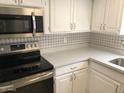 Bright kitchen features stainless steel microwave, white cabinetry, quartz countertops, and a decorative tile backsplash at 15402 N 28Th St # 112, Phoenix, AZ 85032
