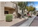 Exterior showcases stairs leading to second-story units, surrounded by gravel and trees at 16013 S Desert Foothills Pkwy # 1133, Phoenix, AZ 85048