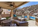 Inviting covered patio with stylish seating and outdoor kitchen, overlooking a pool and picturesque rock wall backdrop at 16834 S 20Th Pl, Phoenix, AZ 85048