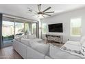 Bright living room boasts an oversized sectional, ceiling fan, and sliding glass doors to the backyard at 21090 E Camina Buena Vis, Queen Creek, AZ 85142