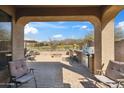 Charming covered patio featuring comfortable seating, outdoor grill, and a view of the picturesque backyard at 2214 W Muirfield Dr, Anthem, AZ 85086