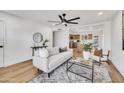 Open living room featuring a comfortable sofa, modern decor, a ceiling fan, and wood floors with an adjacent kitchen at 3037 E Pueblo Ave, Mesa, AZ 85204