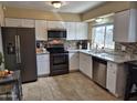 Updated kitchen featuring granite countertops, stainless steel appliances, white cabinets, and modern tile backsplash at 4231 E Roeser Rd, Phoenix, AZ 85040