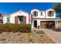 Charming two-story home featuring a red tile roof, stone landscaping, and a three-car garage at 9544 E Theia Dr, Mesa, AZ 85212