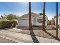 Beautiful single-story home featuring a two-car garage, desert landscaping and mature palm trees along the walkway at 17406 N 28Th Dr, Phoenix, AZ 85053