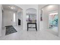 Bright foyer with marble floors, arched doorways, and a charming display shelf for trophies and decorative items at 17687 W Surrey Dr, Surprise, AZ 85388