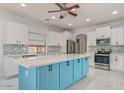 Modern kitchen featuring white cabinetry, stainless steel appliances, a stylish blue island, and a complementary backsplash at 17687 W Surrey Dr, Surprise, AZ 85388