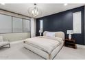 Modern bedroom with a large window, navy blue accent wall, chandelier and hardwood floors at 1936 W Kinfield Trl, Phoenix, AZ 85085