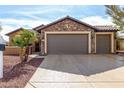 Exterior view of a two-car garage with stone accents and well-maintained driveway at 20515 N 271St Ave, Buckeye, AZ 85396