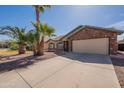 Charming brick home featuring desert landscaping, a two-car garage and mature palm trees in front yard at 4873 E Magnus Dr, San Tan Valley, AZ 85140
