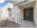 Inviting entryway with arched windows, pergola, and custom front door with palm tree design at 5202 E Marconi Ave, Scottsdale, AZ 85254