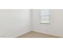 A cozy bedroom with neutral carpet, fresh white paint, and a window with blinds at 7449 W Buckhorn Trl, Peoria, AZ 85383