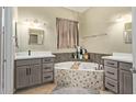 Luxurious bathroom features a soaking tub with decorative tile and dual vanities with grey cabinets at 9716 N 3Rd Dr, Phoenix, AZ 85021