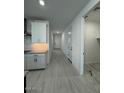 Hallway featuring neutral walls, white doors, wood look flooring, and storage at 10035 S 23Rd Dr, Phoenix, AZ 85041