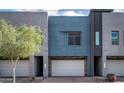 Modern townhome boasts a striking blue facade, garage, and well-maintained landscaping at 1953 W Kinfield Trl, Phoenix, AZ 85085