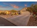 Well-maintained home with a desert landscape, a wide driveway, and charming curb appeal at dusk at 715 E Blossom Rd, San Tan Valley, AZ 85143