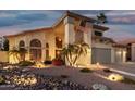 Stunning two-story home with a three-car garage, mature landscaping, and inviting exterior lighting at twilight at 826 W Royal Palms Dr, Gilbert, AZ 85233