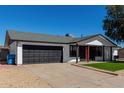 Well-maintained single-story home with a black garage door and artificial turf front yard at 8602 W Clarendon Ave, Phoenix, AZ 85037