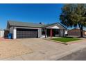 Well-maintained single-story home with a black garage door and artificial turf front yard at 8602 W Clarendon Ave, Phoenix, AZ 85037