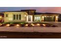 Exterior view of home at twilight with manicured front lawn, flower bed, and decorative lighting at 15936 W Bonitos Dr, Goodyear, AZ 85395