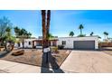 Inviting single-story home with desert landscaping, attached garage, and neatly paved driveway at 6729 E Sharon Dr, Scottsdale, AZ 85254