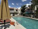 Community pool surrounded by lounge chairs, umbrellas, and manicured landscaping at 985 N Granite Reef Rd # 134, Scottsdale, AZ 85257