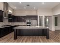 Modern kitchen with stainless steel appliances, dark cabinetry, large island, and stylish backsplash at 13653 W Crabapple Dr, Peoria, AZ 85383