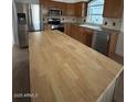 Well-lit kitchen with stainless steel appliances, wood cabinets, and a butcher block island at 15659 W Ripple Cir, Goodyear, AZ 85338