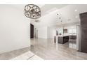 Spacious living room with modern lighting fixtures, tile floors, white walls, and an open floor plan to the kitchen at 22167 W Laura St, Wittmann, AZ 85361