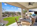 Covered outdoor patio featuring a dining table, seating area, and views of the landscaped backyard at 3074 N 167Th Dr, Goodyear, AZ 85395