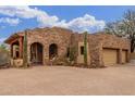 Stunning desert home exterior featuring a gated entrance, two-car garage, and mature cacti at 10955 E Vista Del Cielo Rd, Gold Canyon, AZ 85118