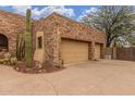 Close-up of an attached two-car garage with stone exterior and desert landscaping at 10955 E Vista Del Cielo Rd, Gold Canyon, AZ 85118