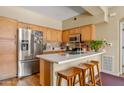 Bright kitchen featuring stainless steel appliances, breakfast bar with wooden stools, and wood cabinetry at 1351 N Pleasant Dr # 1045, Chandler, AZ 85225