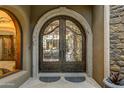 Ornate wrought iron double front doors with arched stone surround and detailed stonework at 14371 E Kalil Dr, Scottsdale, AZ 85259