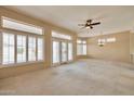 Bright living room featuring plush carpeting, multiple windows with shutters, and a ceiling fan at 14936 W Yosemite Dr, Sun City West, AZ 85375