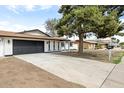 Single-story home featuring a brick exterior, a large driveway, and mature trees in a suburban setting at 2032 W Eugie Ave, Phoenix, AZ 85029