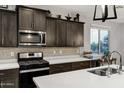 Close-up of the kitchen with stainless steel appliances, dark wood cabinets, and a stylish backsplash at 20780 N Gardenia Rd, Maricopa, AZ 85138