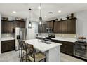 Spacious kitchen featuring dark wood cabinetry, stainless steel appliances, and a large island with seating at 20780 N Gardenia Rd, Maricopa, AZ 85138