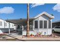 Attractive mobile home featuring a covered carport, inviting porch, and colorful desert landscaping at 384 Gypsum Dr, Apache Junction, AZ 85119