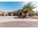 Inviting home with a three-car garage, tiled roof, stone facade, desert landscape and mature tree at 4187 N 183Rd Dr, Goodyear, AZ 85395